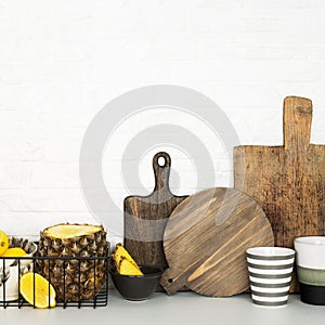 Kitchen shelf with baskets for storing products, pineapple, lemons, cutlery in a glass, chopping wooden boards on a