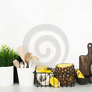 Kitchen shelf with baskets for storing products, pineapple, lemons, cutlery in a glass, chopping wooden boards on a