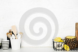 Kitchen shelf with baskets for storing products, pineapple, lemons, cutlery in a glass, chopping wooden boards on a