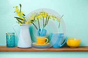 Kitchen shelf with flowers in vase and tableware photo