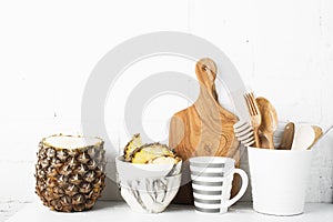 Kitchen shelf lifestyle white background with fresh lemons, pineapple, kitchen tools, appliances, chopping boards