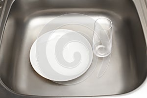 Kitchen sink with clean white plate and drinking glass