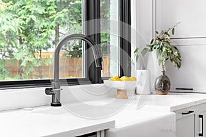 A kitchen sink detail with a black faucet and farmhouse sink.