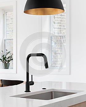 A kitchen sink detail with a black faucet and marble countertop.