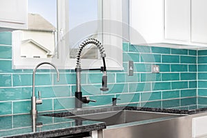 A kitchen sink detail with a blue subway tile backsplash and apron sink.