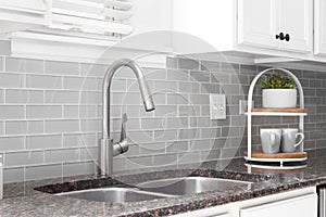 A kitchen sink detail with grey subway tile.