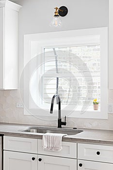 A kitchen sink detail with a hexagon backsplash and white cabinets.