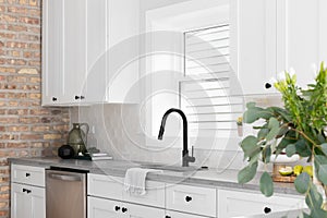 A kitchen sink detail with a hexagon backsplash and white cabinets.