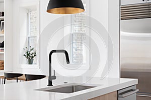 A kitchen sink detail with a modern fixture above a black faucet.