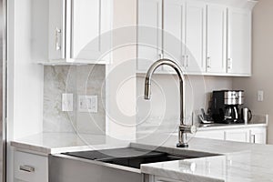 A kitchen sink detail in a white kitchen.