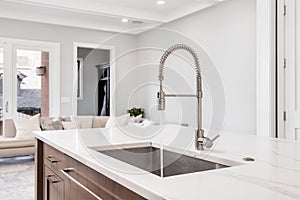 A kitchen sink detail with a wood cabinet and looking out over a living room.