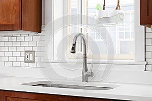 A kitchen sink detail with wood cabinets and subway tile backsplash.