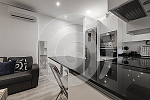 Kitchen with stainless steel appliances, white cabinets with black marble