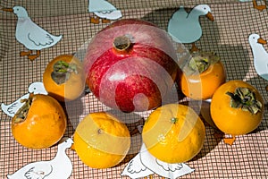 Kitchen still-life. Wholesome ripe fruits of pomegranate, mandarine and persimmon on a cute tablecloth.