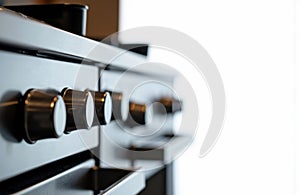 Close-up of a modern kitchen stove with metallic control knobs and a clean