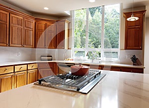 Kitchen stovetop with stone counters, cherry cabinets and a large window with daylight coming in