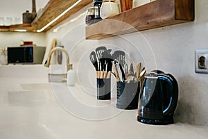 Kitchen stuff and kettle. Bright white modern design of luxury kitchen with wooden shelves