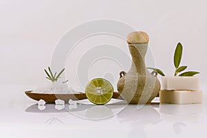 Kitchen supplies isolated on a white background: a plate of salt, lime, granite vase, natural soaps