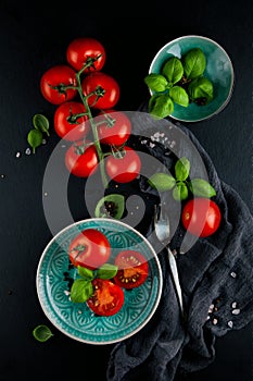 Kitchen table decorated with fresh tomatoes, basil and salt and pepper with fork and napkin