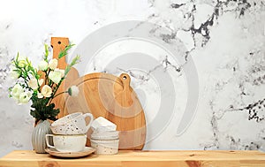 Kitchen table with dishes, cutting boards and spring flowers. Simple home kitchen interior, mockup for product design and display