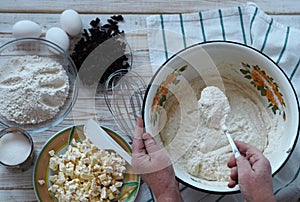 Kitchen table with ingredients for making semolina pie.Hands of an elderly woman kneading dough.Food pastry background