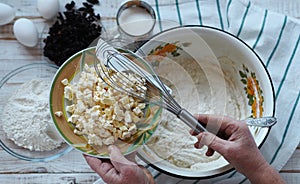 Kitchen table with ingredients for making semolina pie.Hands of an elderly woman kneading dough.Food pastry background