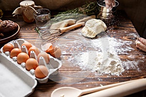 On the kitchen table, a ready-made dough, scattered flour and a tray with eggs.