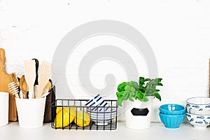 Kitchen table shelf with cutlery, spoons, spatulas, fresh basil, cutting boards, fresh vegetables, lemon on a simple