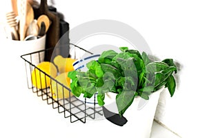 Kitchen table shelf with cutlery, spoons, spatulas, fresh basil, cutting boards, fresh vegetables, lemon on a simple