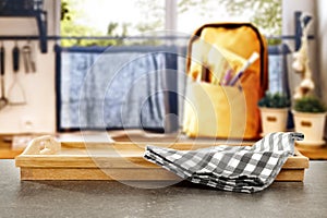 Kitchen table top with empty space for products or decoration, yellow schoolbag, blurred spring outside the window background.