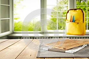 Kitchen table top with empty space for products or decoration, yellow schoolbag, blurred spring outside the window background.