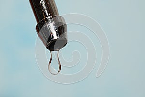 Kitchen tap with water drops on a light-blue backg