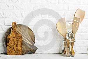 Kitchen tools, olive cutting board on a kitchen shelf against a white brick wall. selective focus