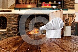 Kitchen tools on wooden top with cosy warm home interior with old fireplace wall background.