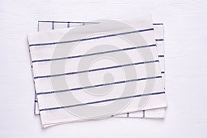 Kitchen towels with blue stripes on white wooden table top. Mock up for design photo
