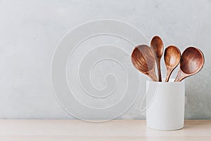 Kitchen utensils background. Wooden spoons in a white jug on light background with copy space