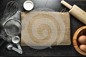 Kitchen utensils and baking ingredients: egg and flour on black background.