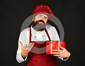 Kitchen utensils concept. Cook with doubting face holds red pot
