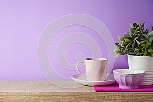 Kitchen utensils and dishware on wooden shelf. Kitchen interior purple background