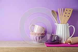 Kitchen utensils and dishware on wooden shelf. Kitchen interior purple background
