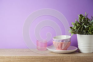 Kitchen utensils and dishware on wooden shelf. Kitchen interior purple background