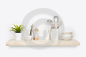 Kitchen utensils, flower pot and dishware on natural wooden shelf