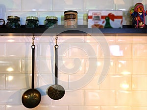 Utensils hanging on the kitchen of a restaurant next to a shelf with spices