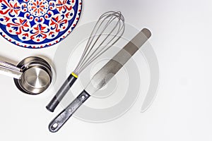 Kitchen utensils, measuring cups, whisk , and spatula on white background