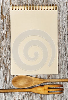 Kitchen utensils and paper spiral notebook on the old wood