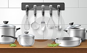 Kitchen utensils. Realistic cookware on wooden table. Steel pots with glass lids and pans, cooking accessories skimmer