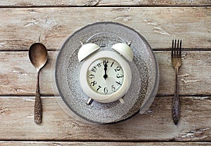 Kitchen utensils- spoon, fork, plate and alarm on old wooden table
