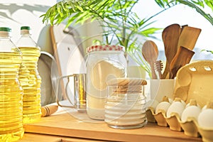 Kitchen utensils, sunflower oil, flour, eggs on wooden table in pantry