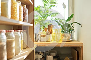 Kitchen utensils, sunflower oil on wooden table in pantry, food storage at home