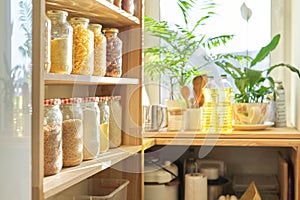 Kitchen utensils, sunflower oil on wooden table in pantry, food storage at home